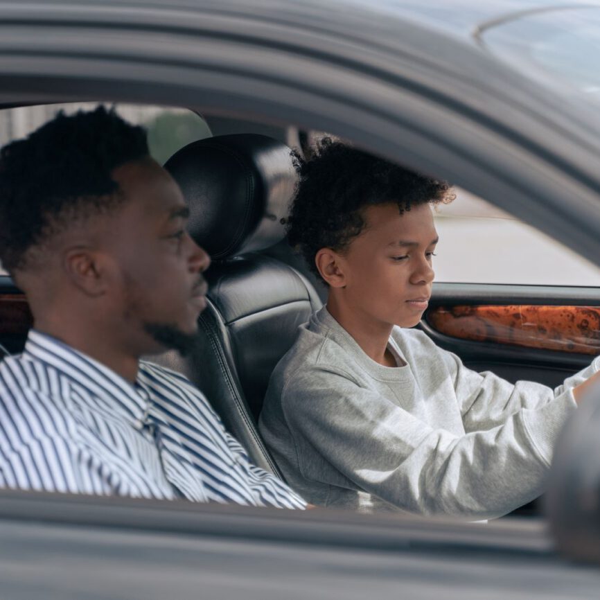 Élève au volant, accompagnateur assis à côté, vu par la vitre