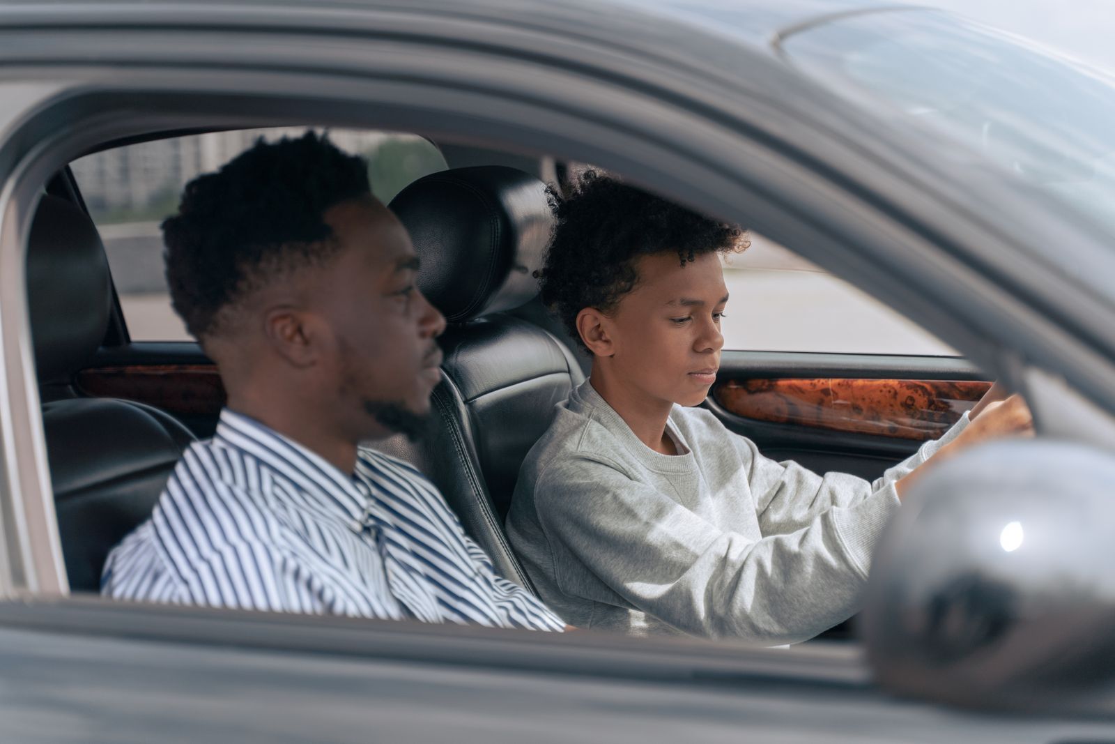 Élève au volant, accompagnateur assis à côté, vu par la vitre
