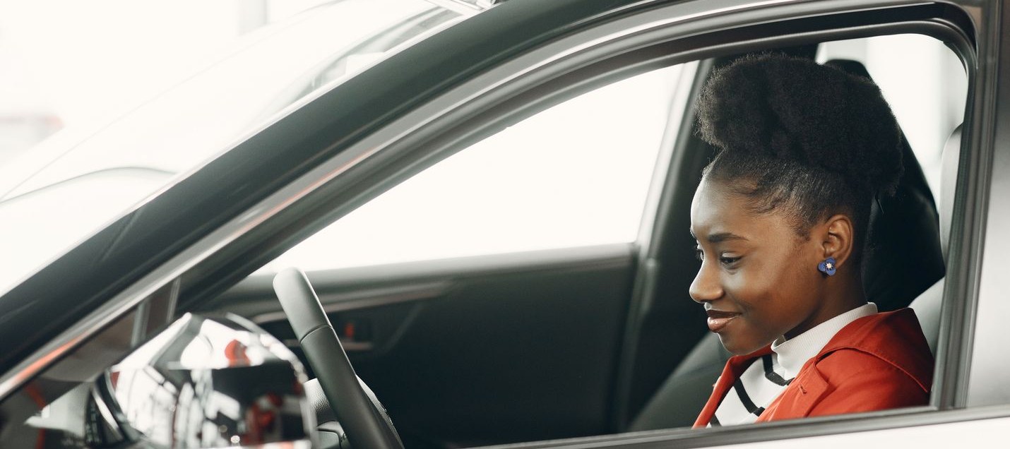 Jeune conductrice souriante au volant, vitre ouverte